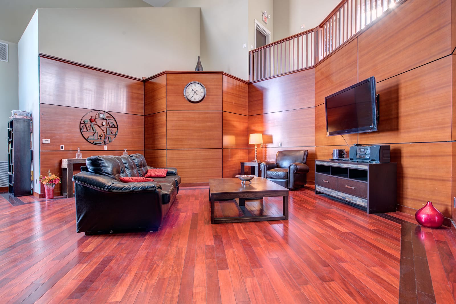 Two-storey party room with leather seating and a wall-mounted TV under the mezzanine