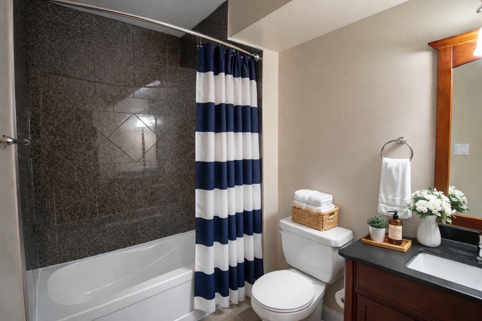 Bathroom with a tiled tub surround, granite vanity top and a framed mirror
