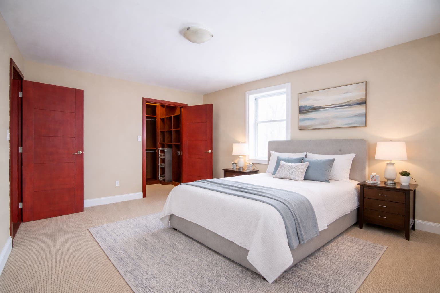 Carpeted bedroom with a walk-in closet and a window over the nightstands